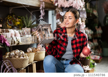 Cheerful young female in casual shirt buying Christmas bulbs before holidays in a store 111540786