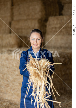 Cheerful woman farmer holding bunch of hay Cheerful woman farmer holding bunch of hay 111541026