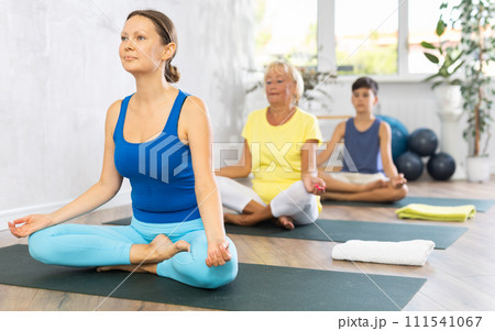 Group of people generation on mats doing yoga exercise lord of fishes pose. Group of people generation on mats doing yoga exercise lord of fishes pose. 111541067