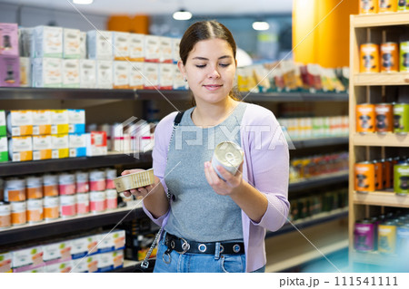 Young happy woman choosing canned pet food in pet shop 111541111