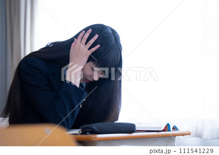 受験や成績などに悩んで頭を抱えて顔を伏せる女子学生 111541229