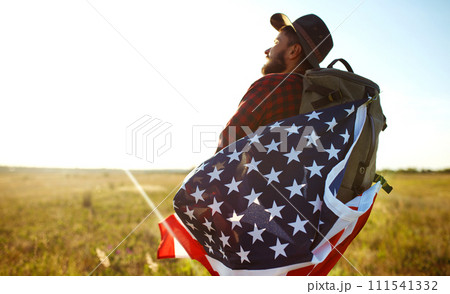 4th of July. American Flag. Traveler with the flag of America. The man in a hat, a backpack, a shirt and jeans. 111541332