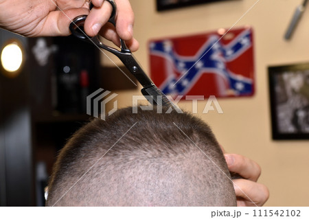 A hairdresser uses scissors to cut hair from a client's head. A hairdresser uses scissors to cut hair from a client's head. 111542102