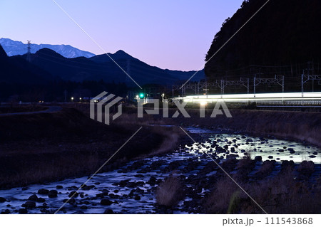夕暮れの東武日光線と雪化粧した女峰山 111543868