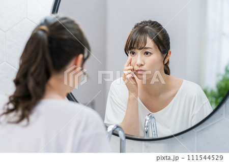 鏡の前で肌の状態をチェックする女性。 111544529