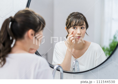 鏡の前で肌の状態をチェックする女性。 111544530