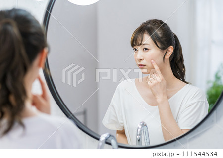 鏡の前で肌の状態をチェックする女性。 111544534