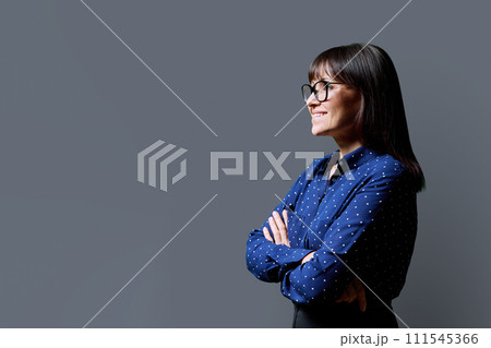 Profile view of middle aged smiling woman, gray background, copy space 111545366