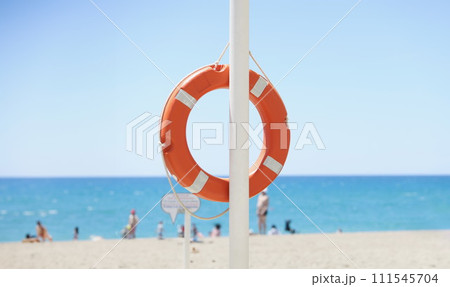 A red lifebuoy hangs on the beach, blurry 111545704