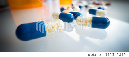 White blue capsules lie on the table, blurry 111545835