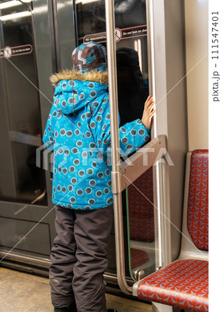 Young boy leaning against subway car doors, looking out the window Young boy leaning against subway car doors, looking out the window 111547401