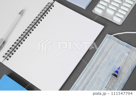 Empty gray modern doctor desk table with mask, notepad, syringe. Copy space, flat lay. Top view. Medicine and healthcare, cardiology, medical education. Blank space for text. Paper sheet for text 111547704