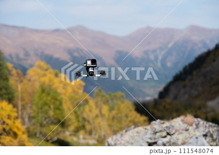 FPV drone hovering in the air, filming a forest in the mountains with an action camera attached to the drone 111548074