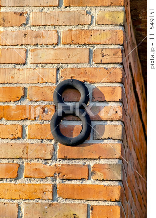 Brick wall with black number 8 on it's side and brick wall behind it. 111549151
