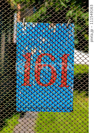 There is a blue sign with the number 161 in red hanging on the fence. 111549163