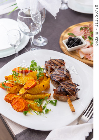 Grilled meat on a skewer with a side dish of vegetables and French fries Grilled meat on a skewer with a side dish of vegetables and French fries 111550720
