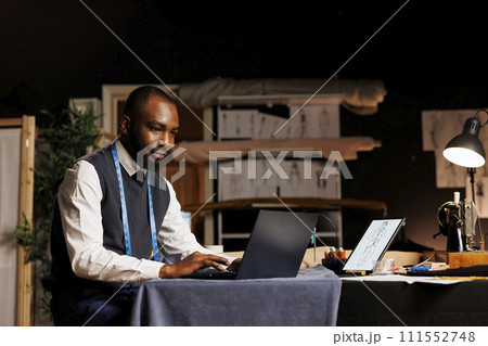 Smiling couturier in online video call meeting with client, discussing required adjustments for comissioned suit. Expert suitmaker chatting with customer about his bespoke sartorial outfit order 111552748