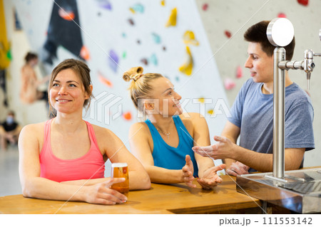 Two sports women and a guy drink tea or coffee after training at climbing wall 111553142