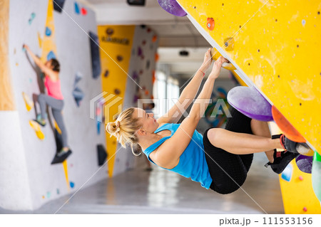 Woman grabbing ledges of artificial climbing wall 111553156