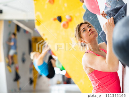 Female mountaineer climbing artificial rock wall without belay indoors Female mountaineer climbing artificial rock wall without belay indoors 111553166