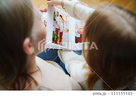 mother and daughter flips through a book with photos of dad and pregnant mom. mother and daughter flips through a book with photos of dad and pregnant mom. 111555585