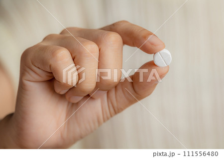 Close up of a female hand holding a pill Close up of a female hand holding a pill 111556480