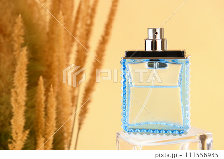 blue glass spray perfume bottle and autumn grass on yellow background. mockup, template, front view blue glass spray perfume bottle and autumn grass on yellow background. mockup, template, front view 111556935