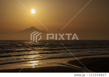 夕陽に染まる海と山影に沈む太陽 111558927