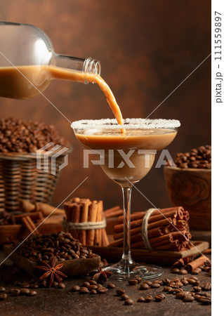 Irish cream and coffee liqueur is poured from a bottle into a glass. 111559897