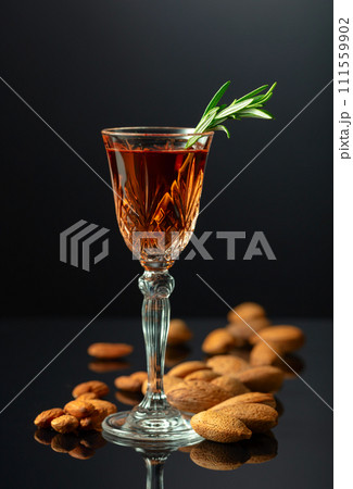 Italian liqueur Amaretto with almonds nuts on a black background. Italian liqueur Amaretto with almonds nuts on a black background. 111559902