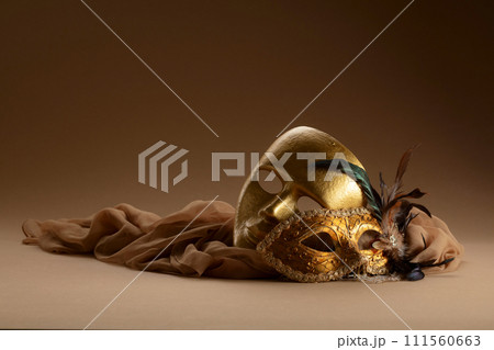 Golden Venetian carnival masks on a beige background. 111560663