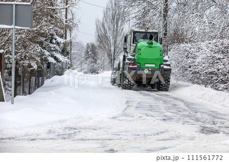 Tractor clears snow on road after heavy snowfall, road maintenance in winter season Tractor clears snow on road after heavy snowfall, road maintenance in winter season 111561772