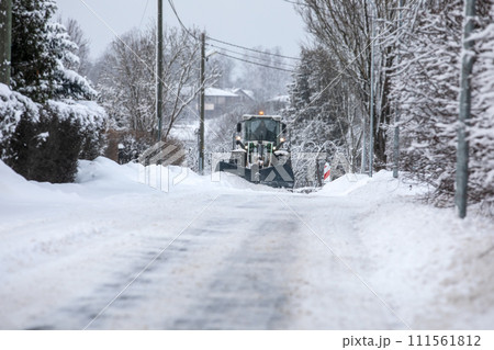 Tractor clears snow on road after heavy snowfall, road maintenance in winter season, harsh weather Tractor clears snow on road after heavy snowfall, road maintenance in winter season, harsh weather 111561812