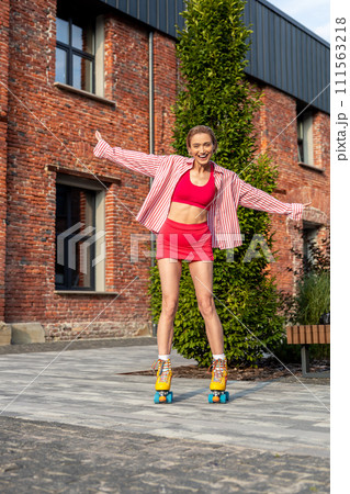 Smiling young woman in bright clothes skating 111563218