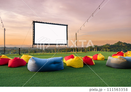 open air cinema with colorful bean bag. empty white screen, free space for text or montage open air cinema with colorful bean bag. empty white screen, free space for text or montage 111563358