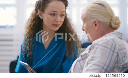 Private duty nurse teaching senior lady how to use a tablet, personal home care 111563950