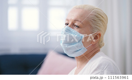 Upset mature woman in a protective face mask sitting lonely in a doctor's office hall Upset mature woman in a protective face mask sitting lonely in a doctor's office hall 111563961
