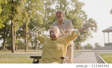 Excited aged couple having fun together in city park, life with disability 111564392