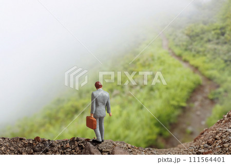 霧中の山道を歩く一人のビジネスマン 111564401
