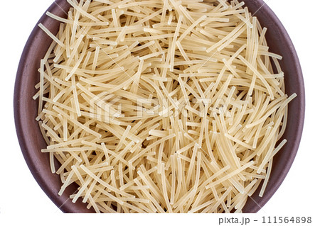 Small egg noodles in brown clay bowl isolated on white background Small egg noodles in brown clay bowl isolated on white background 111564898