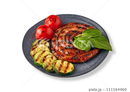 Fried spiral sausage with grilled vegetables and basil on a ceramic plate isolated on a white background Fried spiral sausage with grilled vegetables and basil on a ceramic plate isolated on a white background 111564960