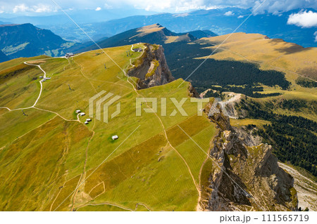 Steep slope of Seceda mountain covered with green grass on sunny summer day. Giant ridgeline in highland of touristic Alps aerial view 111565719