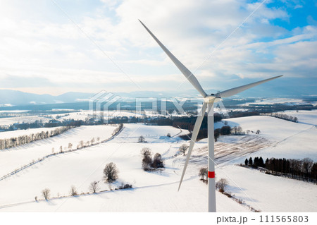 Wind mills or wind turbines in the field in winter with mountains on the background. Wind mills or wind turbines in the field in winter with mountains on the background. 111565803