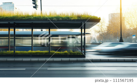 Side view of bus stop with green roof near the roadnd cars passing by in blur with cityscape at the background 111567195