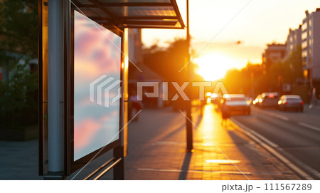 Bus stop near the road with empty banner mockup and cars waiting at a traffic light with sunset cityscape at the background 111567289