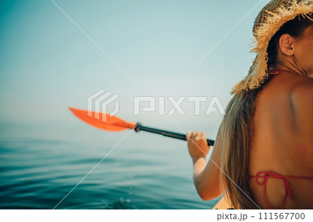 Woman in kayak back view. Happy woman with long hair in a swimsuit and hat floating in kayak on the sea. Summer holiday vacation. Summer holidays vacation at sea. Woman in kayak back view. Happy woman with long hair in a swimsuit and hat floating in kayak on the sea. Summer holiday vacation. Summer holidays vacation at sea. 111567700