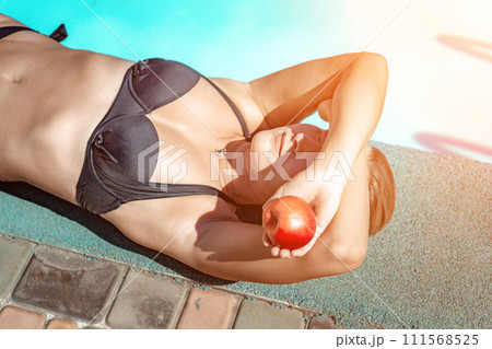 Bikini-clad woman enjoys poolside relaxation. Poolside ambiance. Capturing woman's relaxed time near pool. 111568525