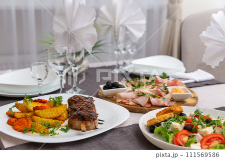 Grilled meat on a skewer, greec salad and meat platter on a served for dinner table. Grilled meat on a skewer, greec salad and meat platter on a served for dinner table. 111569586