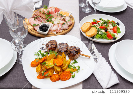 Grilled meat on a skewer, greec salad and meat platter on a served for dinner table. 111569589