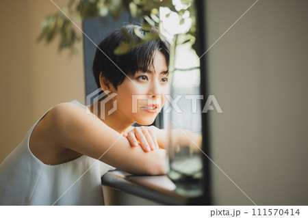 窓辺で夕陽を見る女性　 111570414